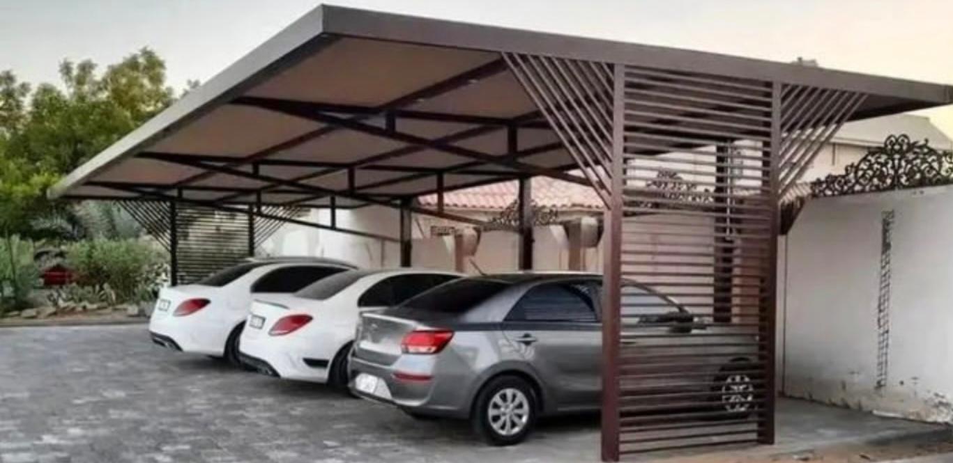 Steel carport shade structure with parked cars at a villa.