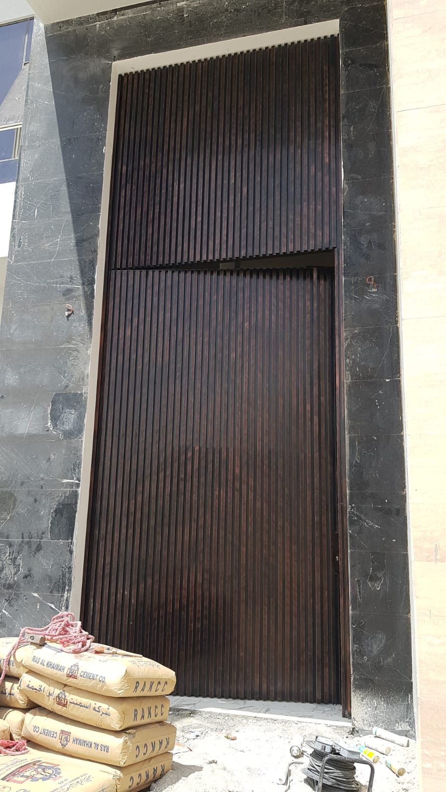 Tall timber-slat feature entrance door set in marble